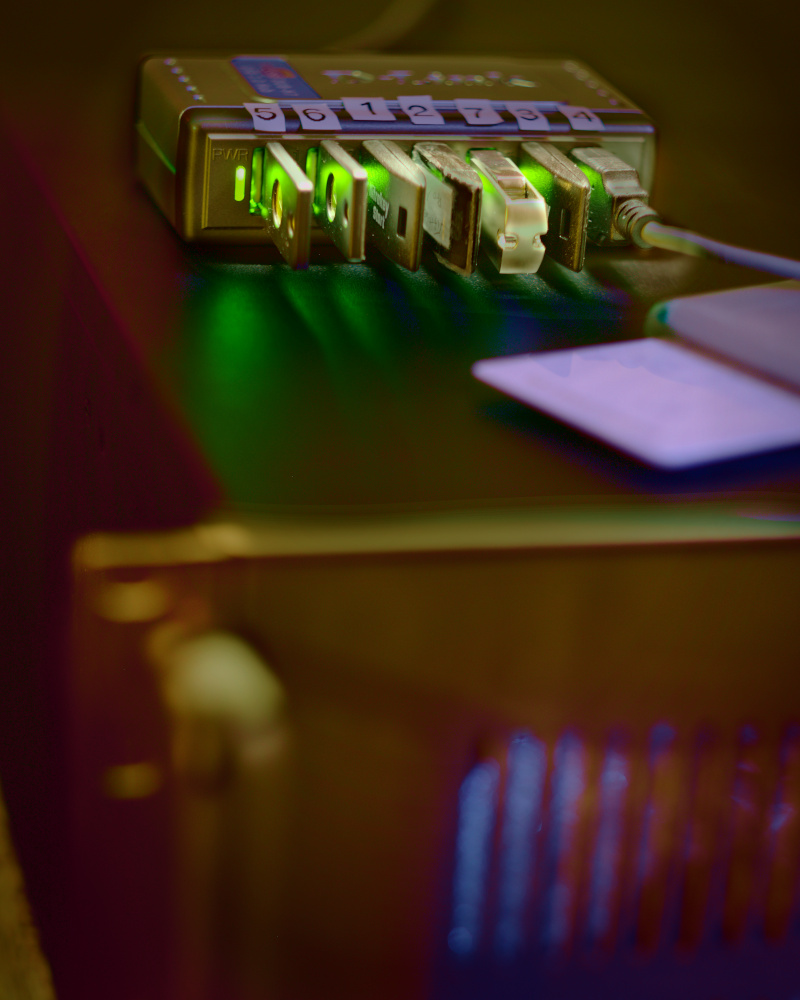 Multiple OpenPGP cards are attached to a USB hub with green 
LEDs. The hub is placed on a black 19" rack server